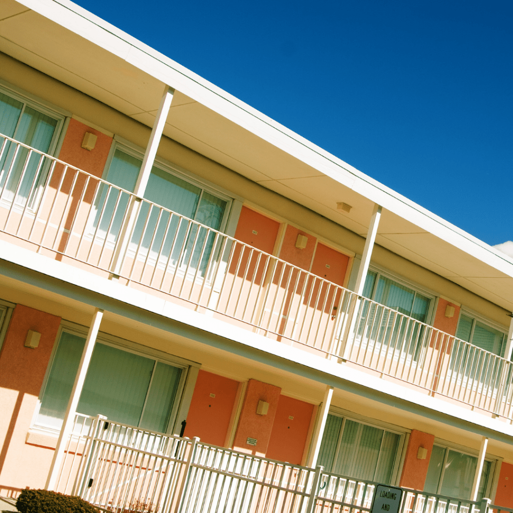 Revenue mit Yielding & Price Optimization für Hotellerie.
Auf dem Bild ist ein Gebäude / Hotel zu sehen mit creme-farbenen Balkongeländern. Die Türen zu den Zimmern sind in Mandarin-Orange und Himmelblau.